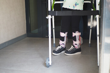  child with walking frame and knee orthosis outdoor 
