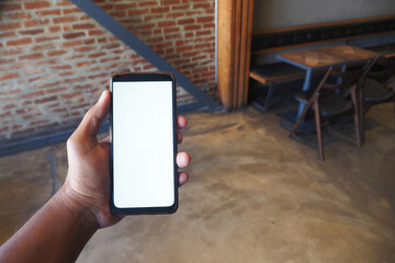 Individual Holding a Smartphone in a Contemporary Cafe Environment, Engaged and Relaxed