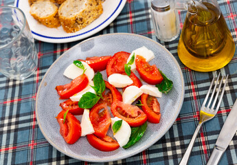 Ready-made dish of Italian cuisine is caprese salad made from slices of mozzarella cheese, slices of ripe tomatoes and basil leaves. Simple and hearty snack, independent dish