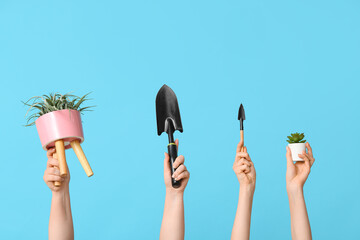 Female hands with plants and gardening shovels on color background