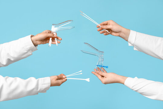 Doctor's hands with pap test tools on blue background