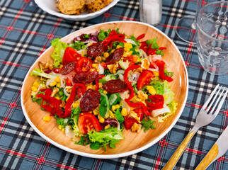 Appetizing salad of fresh vegetables with chorizo, corn and peppers served on platter
