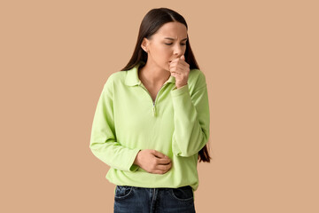 Beautiful young woman suffering from sore throat on brown background