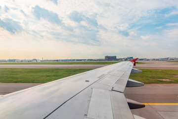 View of airplane wing, blue skies and green land during landing. Airplane window view.