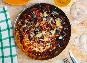 Slices of ham and large amount of grated cheese are added to pizza. During cooking process, food burned, dough became stiff and dark. Burnt pizza with hamon and cheese.