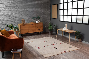 Interior of living room with beige carpet, sofa and drawers