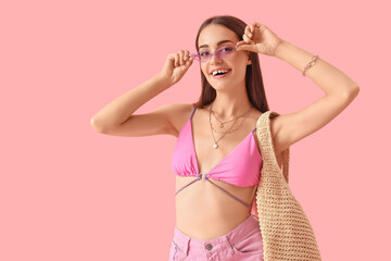 Portrait of fashionable young woman with sunglasses on pink background