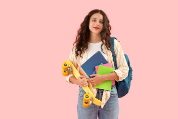 Female student with skateboard on pink background