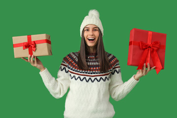 Happy young woman with Christmas gift boxes on green background
