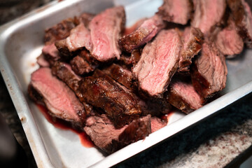 Medium rare pieces of meat resting in plate