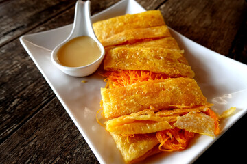Gold Egg Yolk Thread Roti Puff Dessert with milk sauce topping serving on the table.
