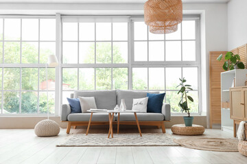 Interior of modern living room with grey sofa and coffee table near window