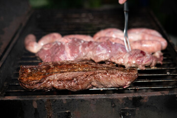 Asado barbecue over grill, cooked and raw close up, fork
