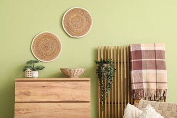 Plaid, wooden chest of drawers and folding screen in interior of beautiful living room