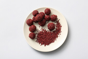 Plate with delicious chocolate truffles and sprinkles on white background