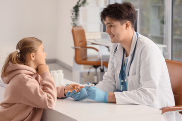 Fototapeta premium Diabetic girl with doctor using lancet pen at table in clinic