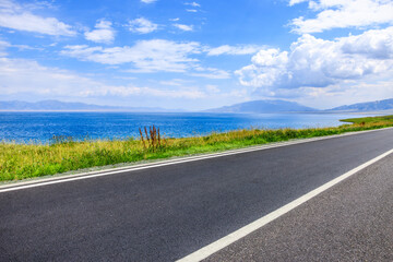 Asphalt road and blue lake natural landscape in summer. Beautiful Sayram Lake scenery in Xinjiang, China. © ABCDstock