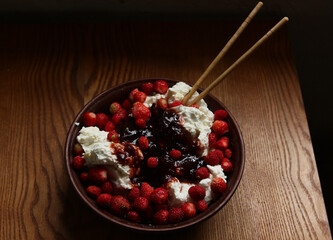 Delicious red fresh strawberries with cottage cheese in a clay plate on a wooden table.