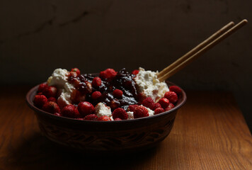 Delicious red fresh strawberries with cottage cheese in a clay plate on a wooden table.