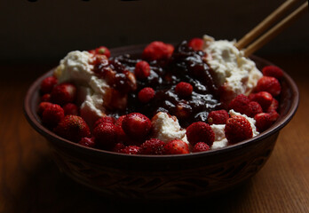 Delicious red fresh strawberries with cottage cheese in a clay plate on a wooden table.
