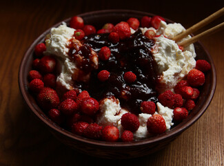 Delicious red fresh strawberries with cottage cheese in a clay plate on a wooden table.