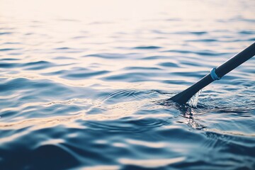 Close-up of a paddle dipping into calm blue water.