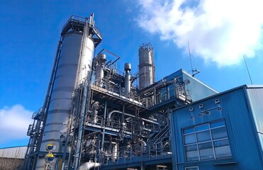 Obraz premium A modern industrial plant with steel pipes and equipment. View of the production line from the outside. An energy production or petrochemical industry concept