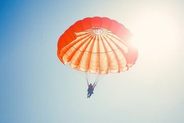 A red and white parachute descends against a bright blue sky with the sun shining through the canopy.