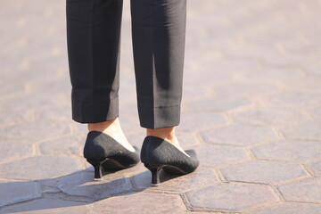 Female legs standing wearing trousers and high heels