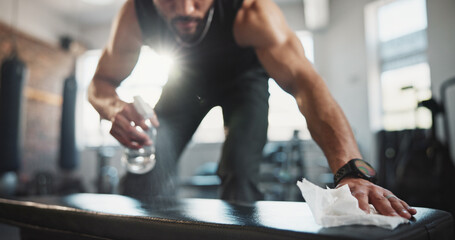 Man, hands and spraying with bottle on gym bench for hygiene, disinfection or sanitary equipment....