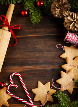 Close-up of star shape Christmas cookie decorations, candy canes, fir branches and pinecones on a wooden table