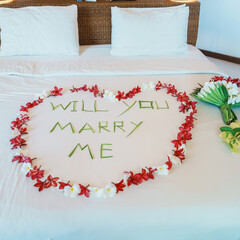 message WILL YOU MARRY ME made of flower petals with bouquet and Heart shape on bed. Idea for marriage proposal, romantic surprise, wedding and engagement concept