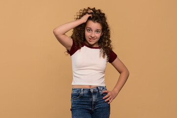 A young girl scratching her head and biting her lip, showing confusion against a beige background