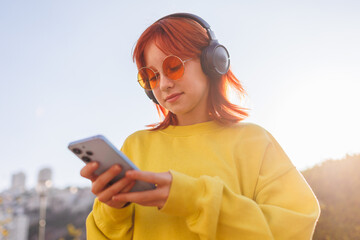 Portrait of a girl with bright hair and facial piercings who uses the phone and listens to music on...