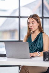 Obraz premium Portrait of young beautiful business asian woman sitting in front of laptop at her desk in workplace office.