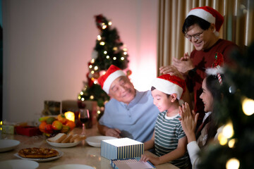 Young Asian beautiful woman and grandfather and dad giving a gift to thire child in christmas party with appreciated moment.happiness in family.