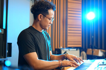 Musician playing music keyboard, Asian man playing piano and practicing in home studio