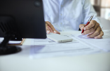 Close-up shot, asian businessman working at office using mobile phone and review document report checking business report or insurance contract before sign