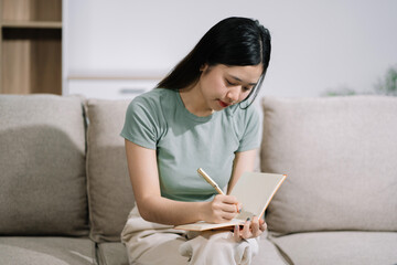 Smiling woman in headphones taking notes, motivated interested student studying online, using tablet, watching webinar training or listening to lecture, remote education concept.