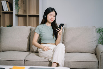 Fototapeta premium Smiling woman in headphones taking notes, motivated interested student studying online, using tablet, watching webinar training or listening to lecture, remote education concept.