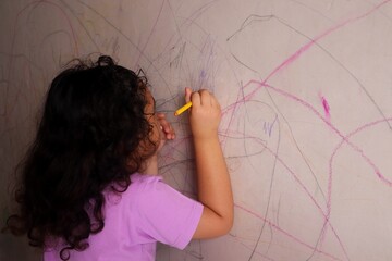 Asian girls are having fun scribbling on the walls using colored pencils.
