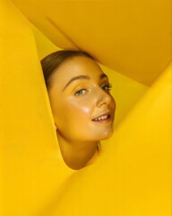 Vibrant Yellow Backdrop Framing a Woman�s Face with a Playful Expression