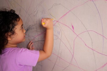 Asian girls are having fun scribbling on the walls using colored pencils.
