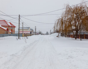 A snowy street with houses in the background