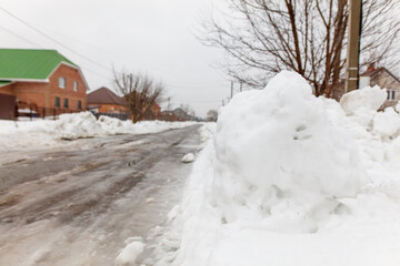 A snowman is sitting on the side of a road in front of a house