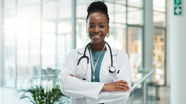 Black woman, doctor and happy with arms crossed at hospital for medical service in Uganda. Female person, portrait and smile or proud in confidence for career growth, healthcare and treatment