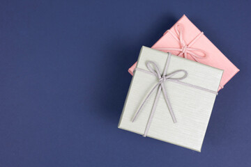 Top view, grey gift box stack on pink gift box over dark blue paper background. Gift box for concept for happy birthday, thank you, congratulation, mother's day, anniversary, Valentine's day.