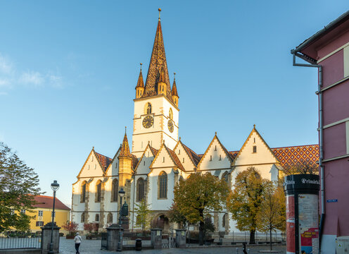 30 october 2024, Sibiu, Romania. Morning view on the Sibiu Lutheran Cathedral, Catedrala Evanghelică Sf&acirc;nta Maria. a female tourist is walking in front of the church. cityscape during autumn. Historic