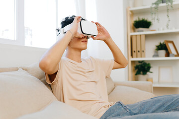 Virtual reality experience, young man wearing VR headset sitting on a cozy couch in a modern room, interacting with immersive content, bright and airy atmosphere