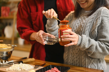 Young couple making pasta sauce for Christmas dinner in a cozy kitchen